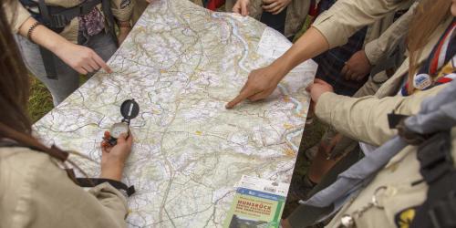 Eine ausgeklappte Landkarte mit Händen die auf bestimmte Stellen zeigen und einen Kompass halten